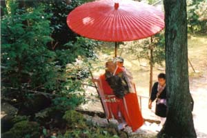 写真：赤い袈裟姿のお坊さんが神社に参拝する写真