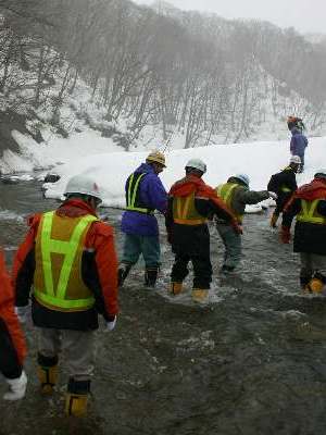 写真：砂子沢ダム安全祈願　道中で川を渡る様子