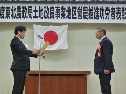 画像：下村東北農政局次長から表彰状を授与される本間代表理事