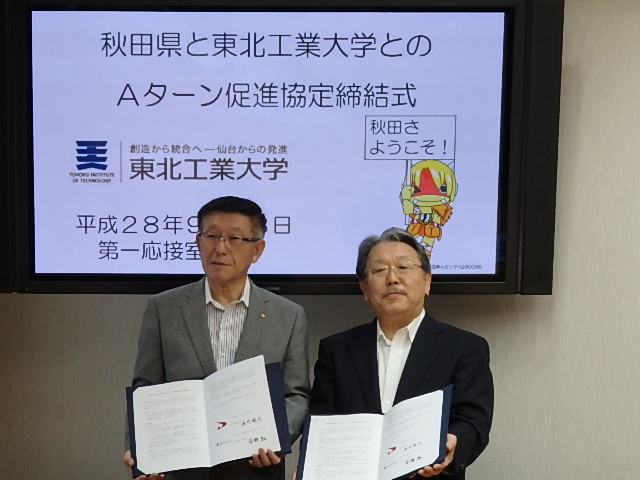 写真：署名した協定書を持ち合う今野学長と佐竹知事