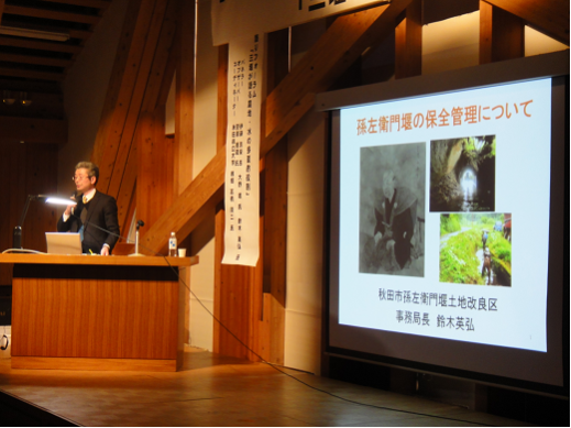 画像:活動報告をする鈴木英弘氏