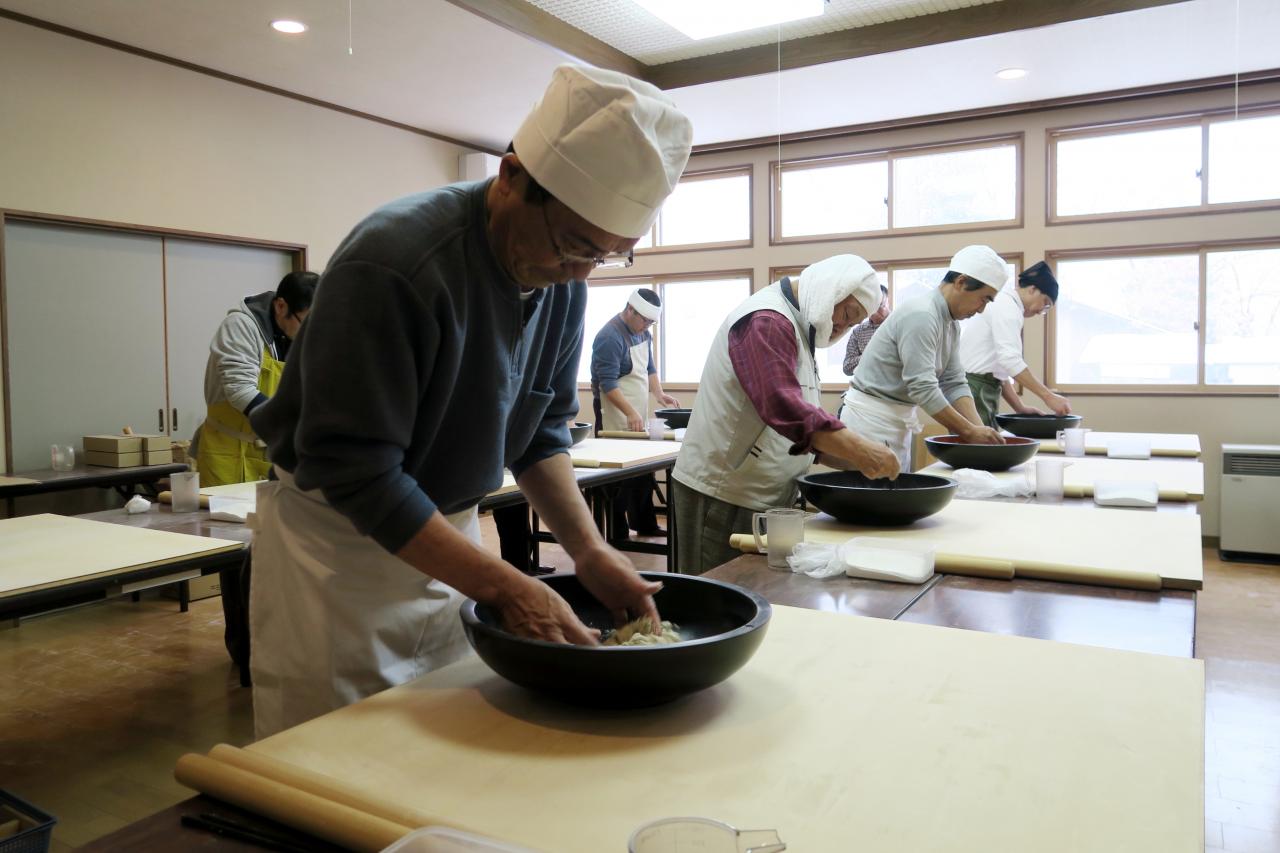 そば粉に水を加える作業「水回し」を行う参加者たち