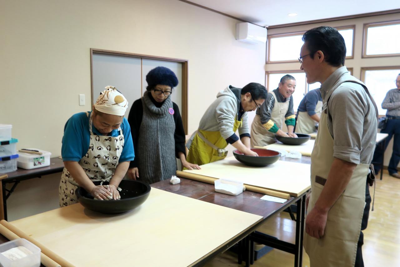 粒状になったそば粉を一塊にする「くくり」の作業をする参加者たち