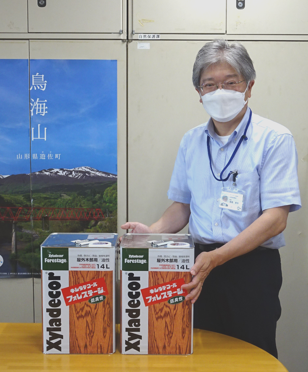 木材防腐塗料「キシラデコールフォレステージ」の提供を受ける県生活環境部自然保護課斎藤課長