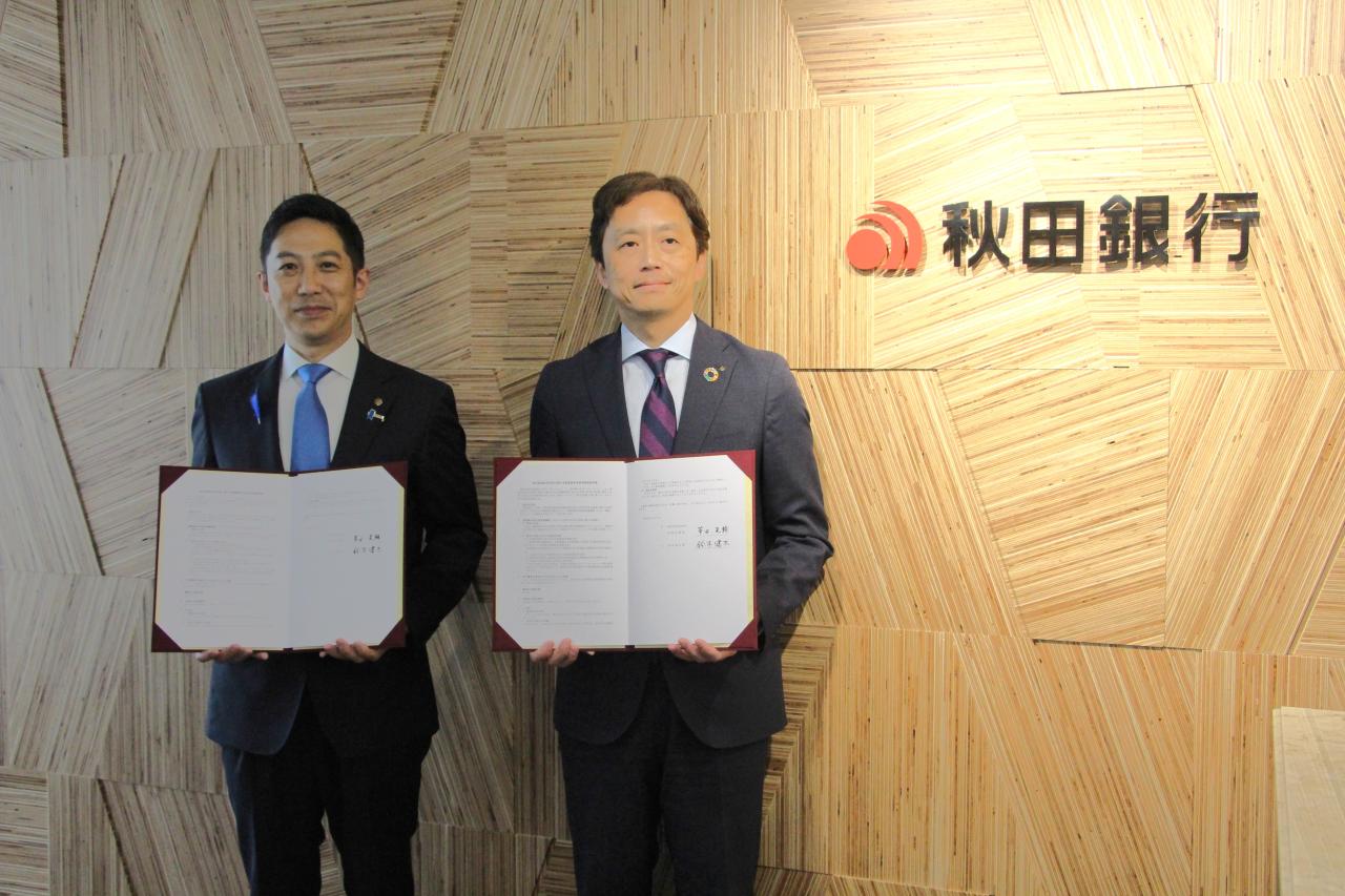 秋田銀行本店１階エントランスの木質化壁面を背景に記念撮影