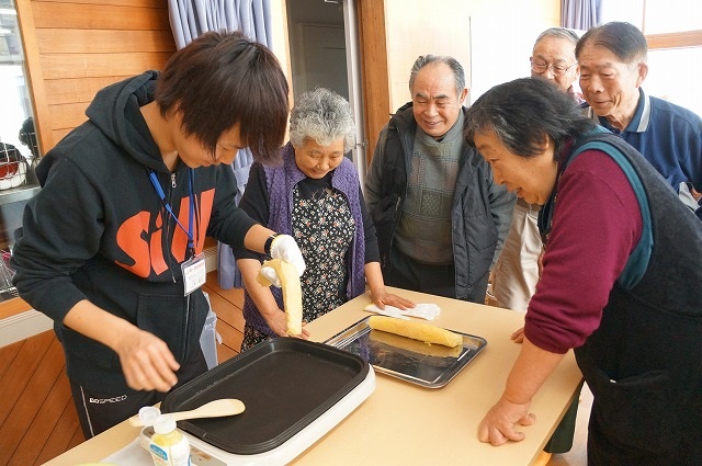 住民と一緒に伝統料理を作る第一学院高等学校の生徒